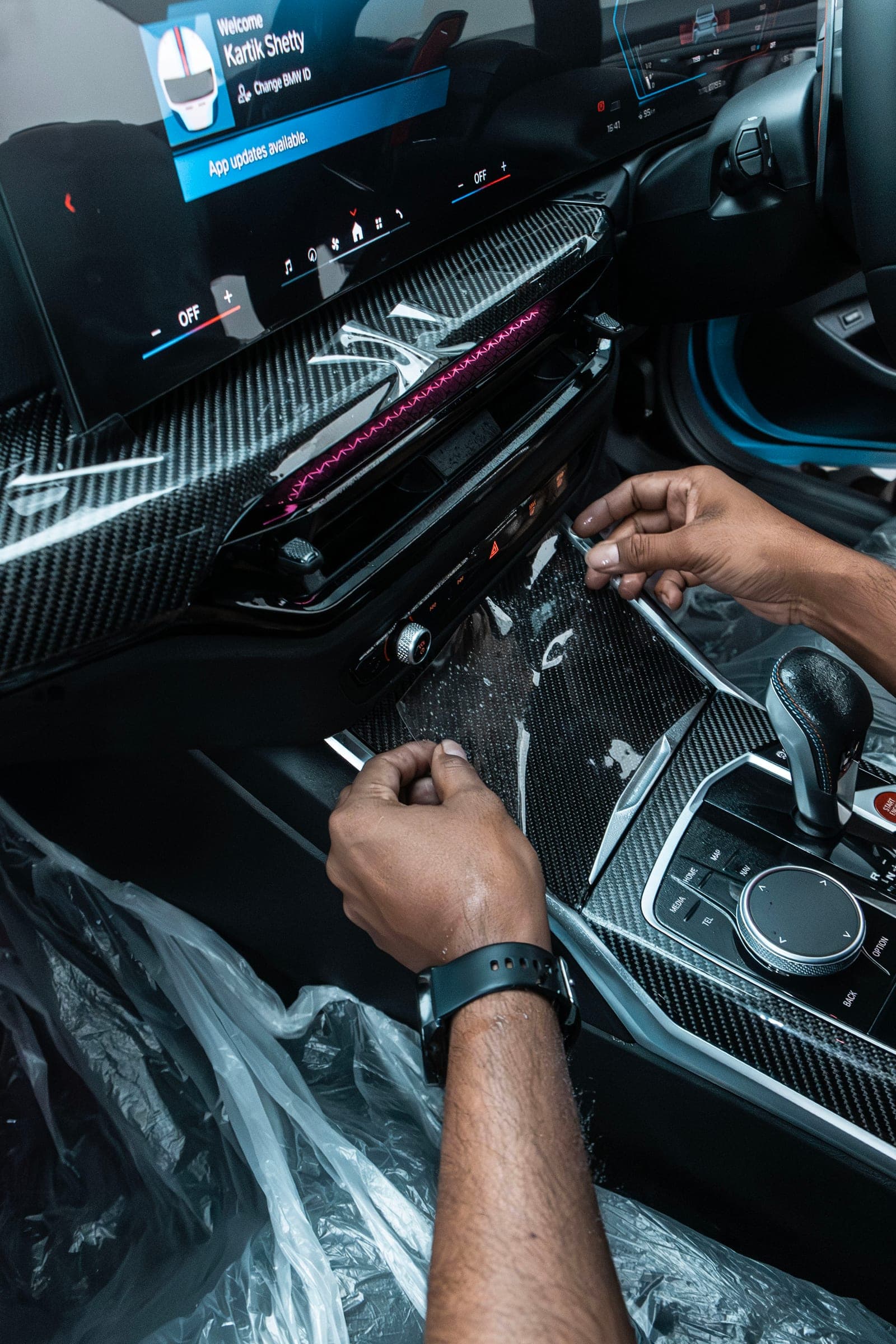 Hands fitting film to the carbon centre console of a BMW M2