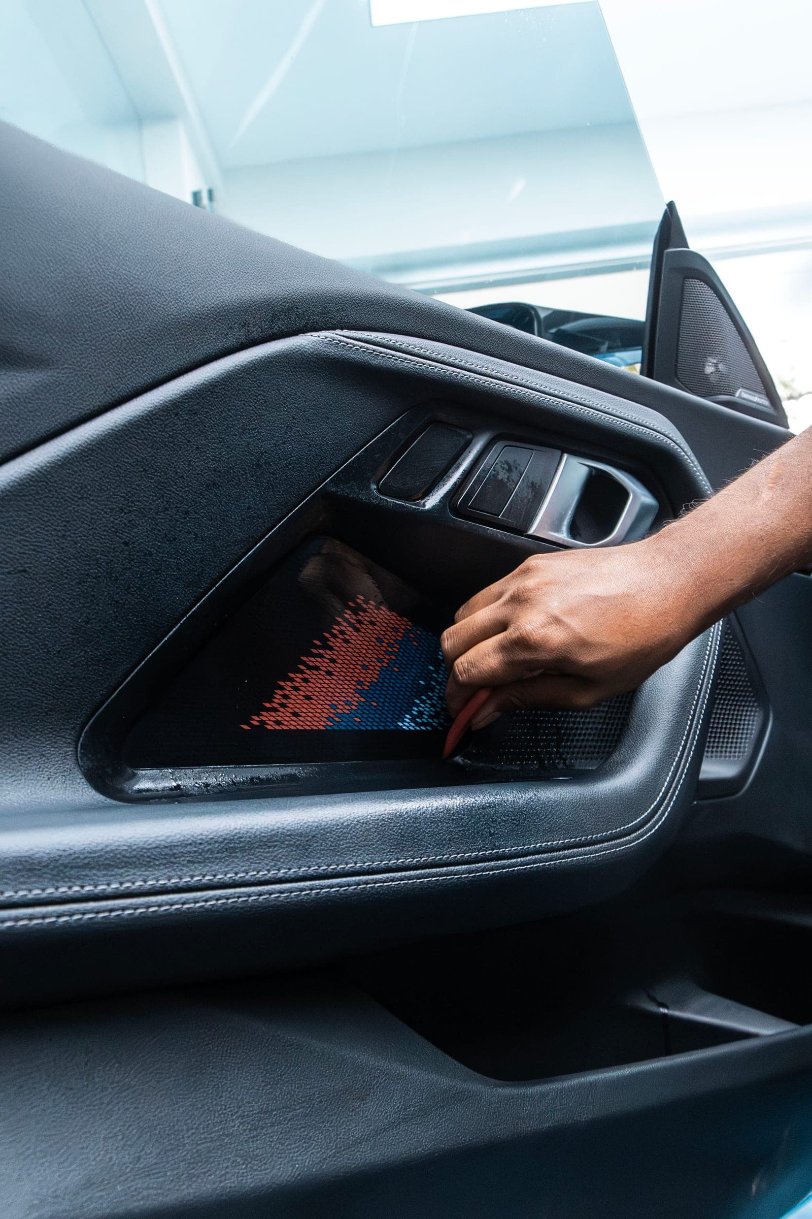 Film being trimmed around the door-card inlay of a BMW M2