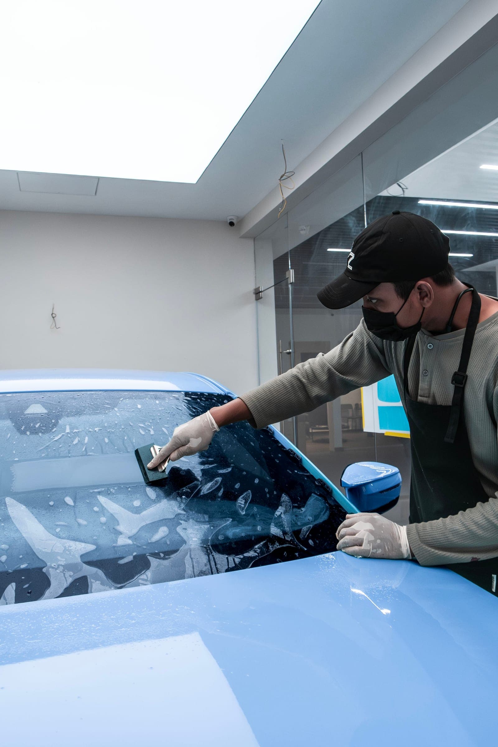 Squeegee chasing water from under windscreen film on a BMW M2