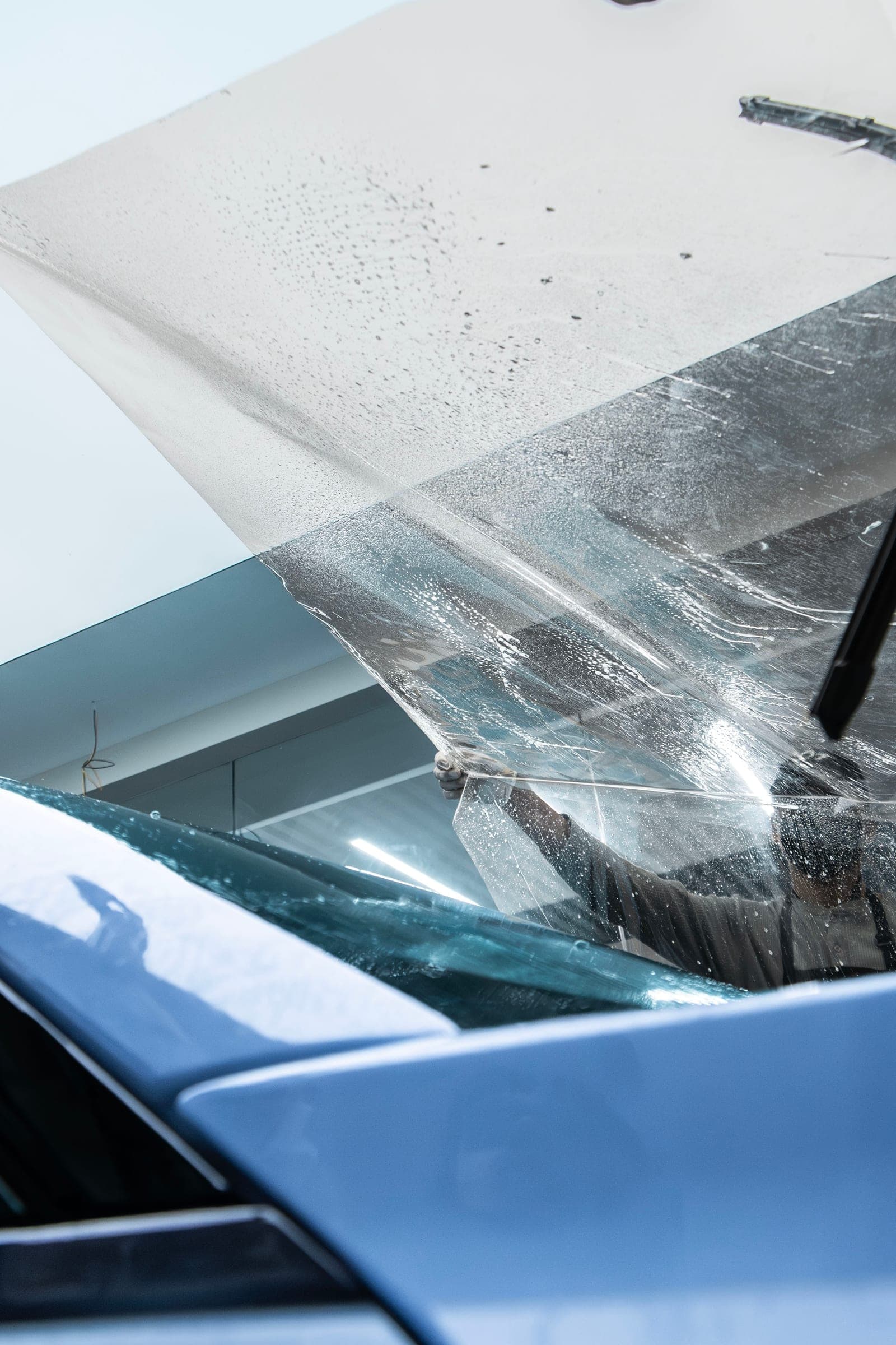 Protective film being laid across the windscreen of a BMW M2