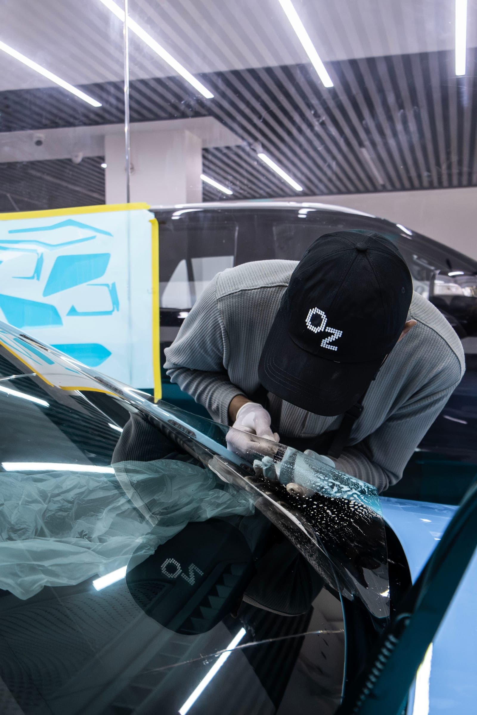 Technician in an Obsidian Zero cap squeegeeing film onto a BMW M2 windscreen