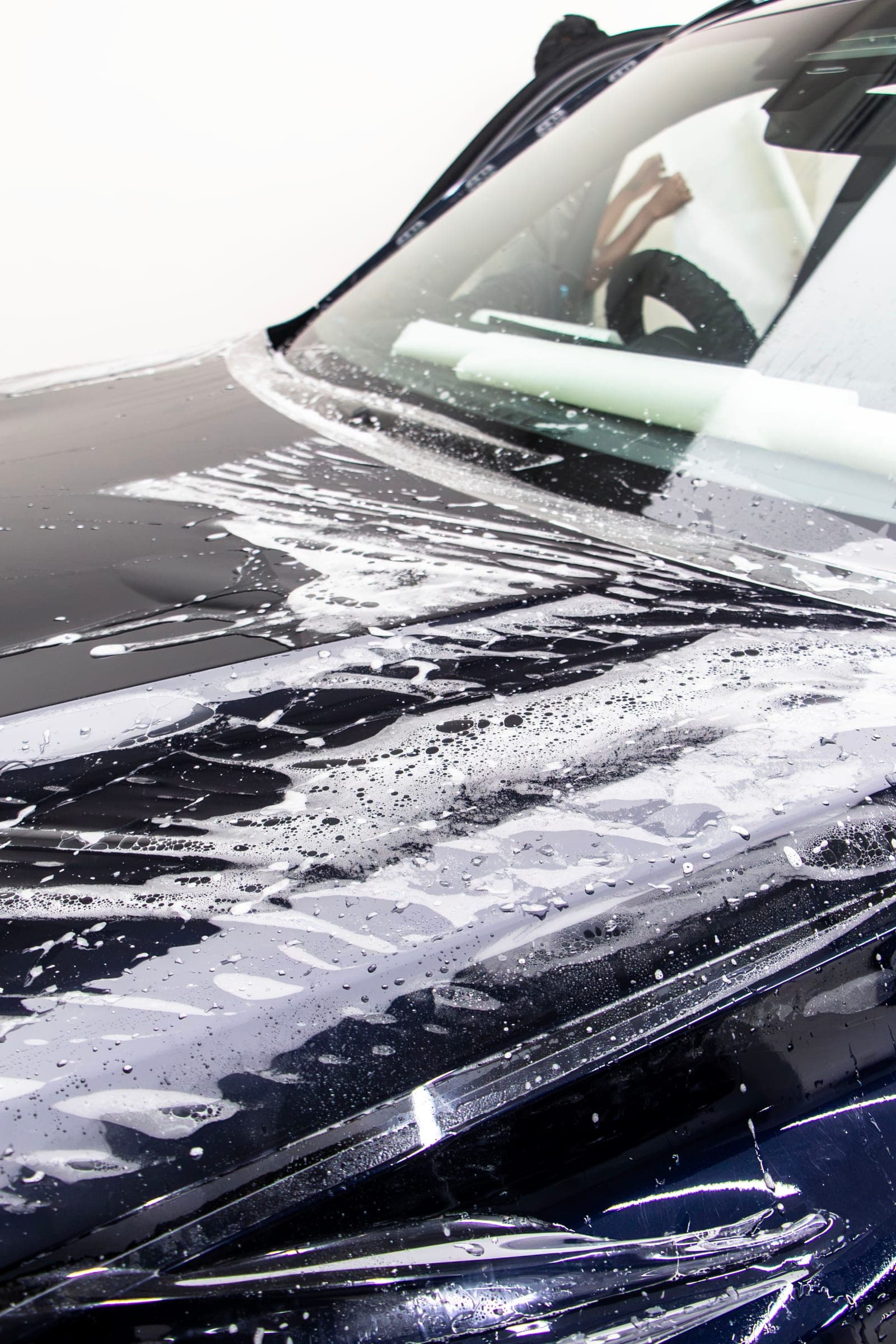 Wet paint protection film being floated across the bonnet of a BMW X5