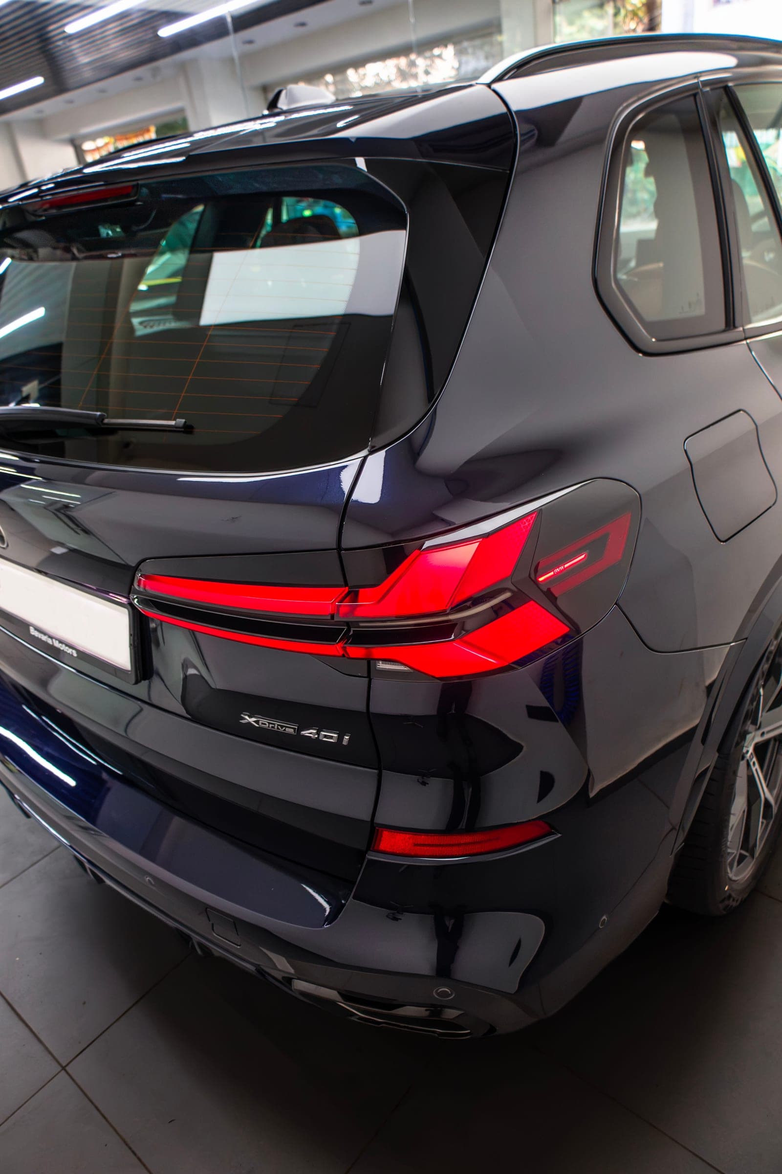 Rear three-quarter of a dark blue BMW X5 with tail-lights lit