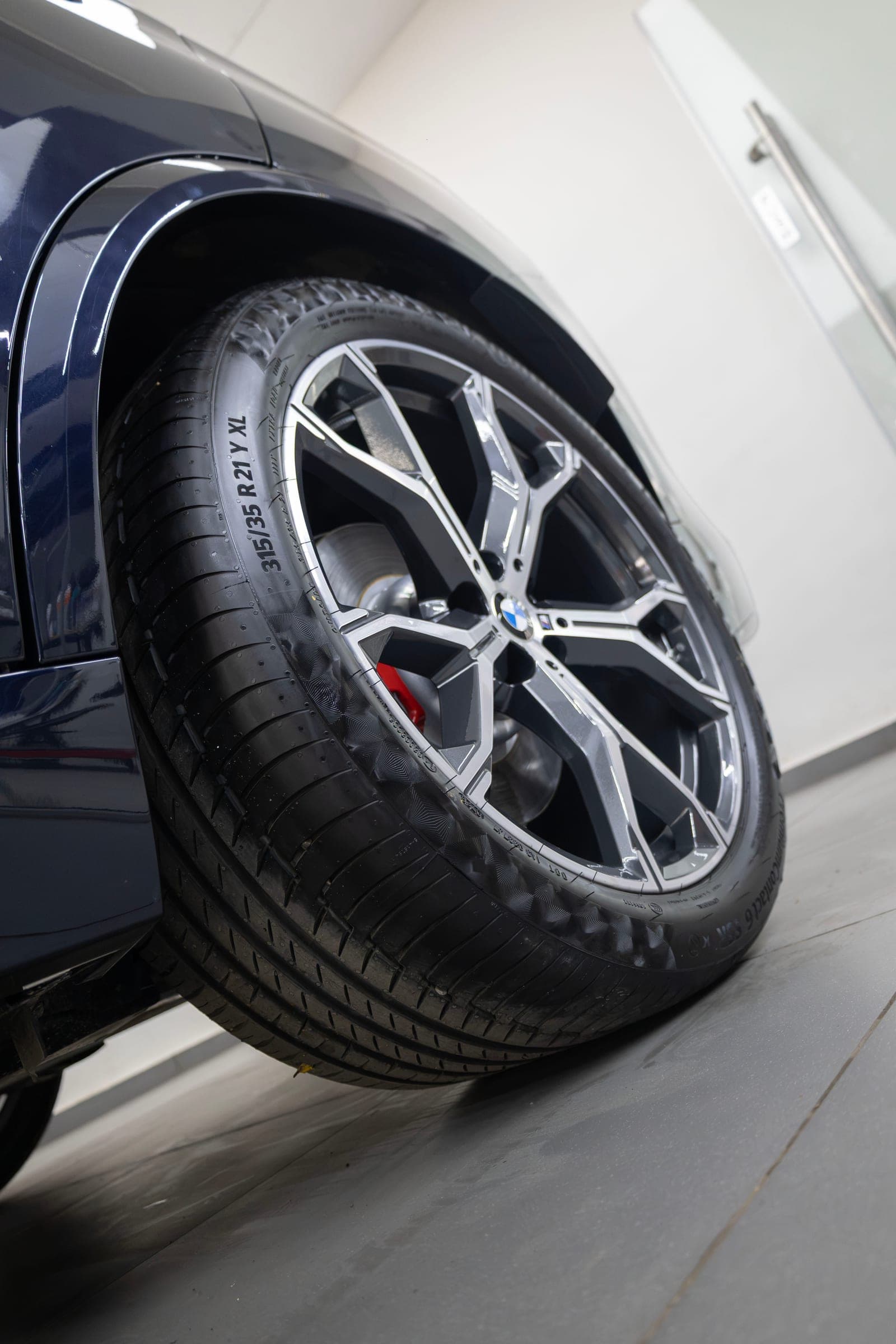 Low-angle view of a BMW X5 alloy wheel and red brake caliper