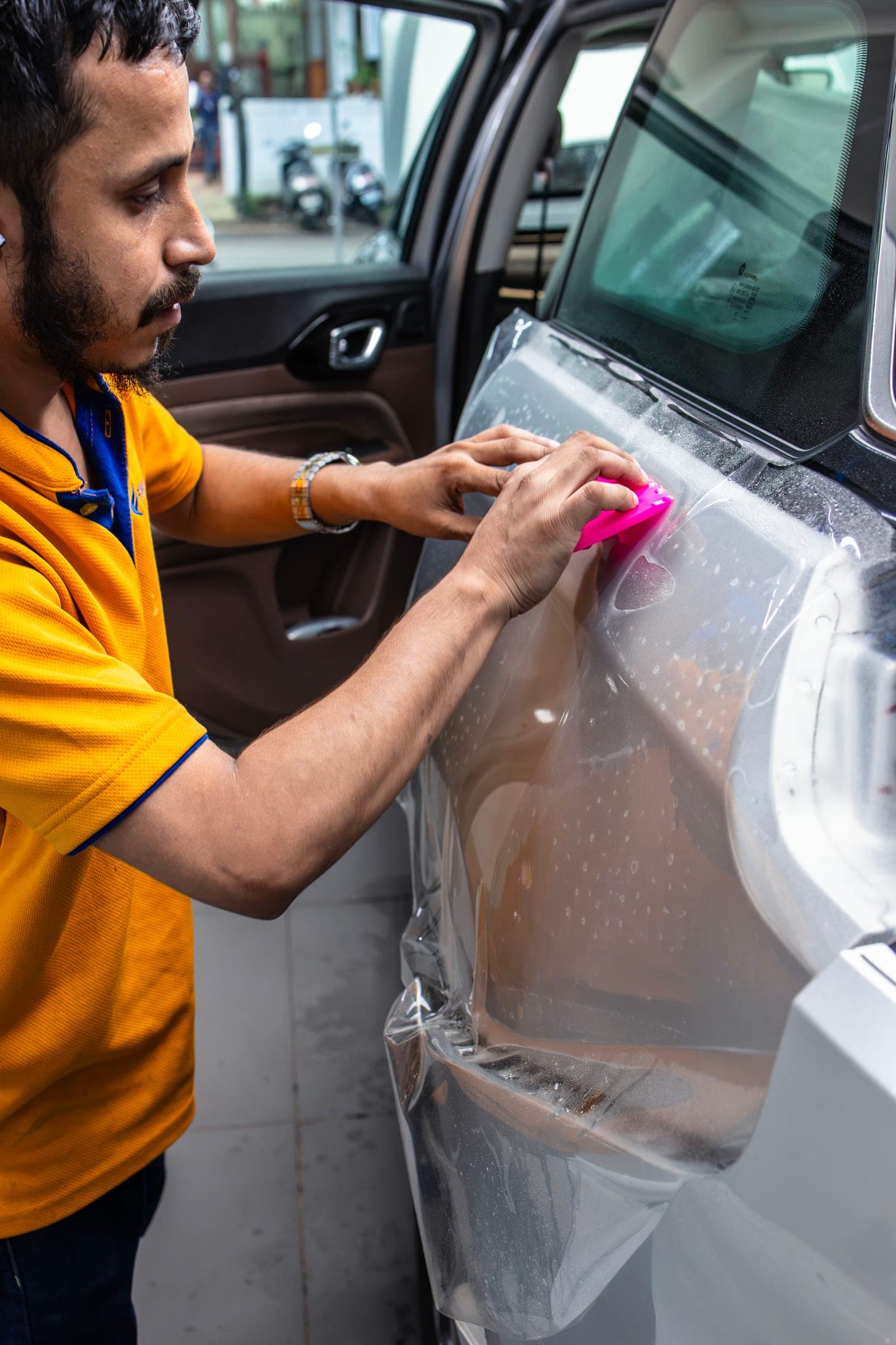 Installer working film onto a rear door with a pink squeegee