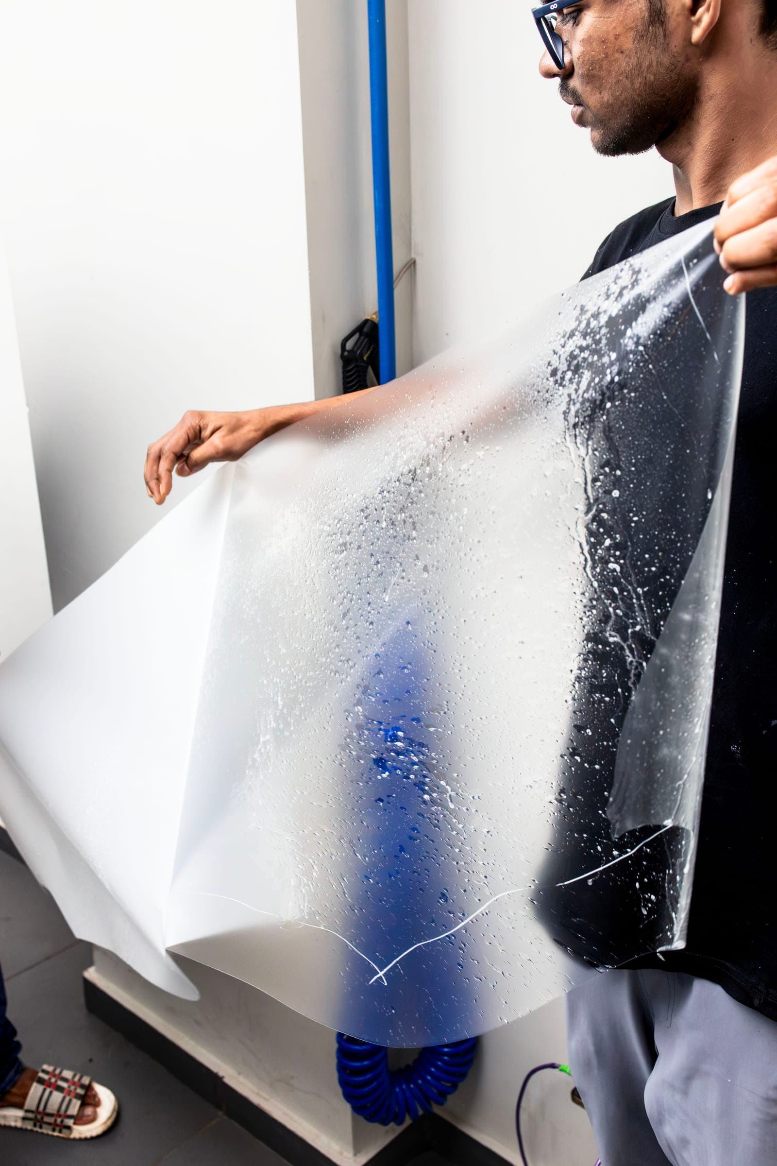 Installer holding a large sheet of paint protection film ready for application