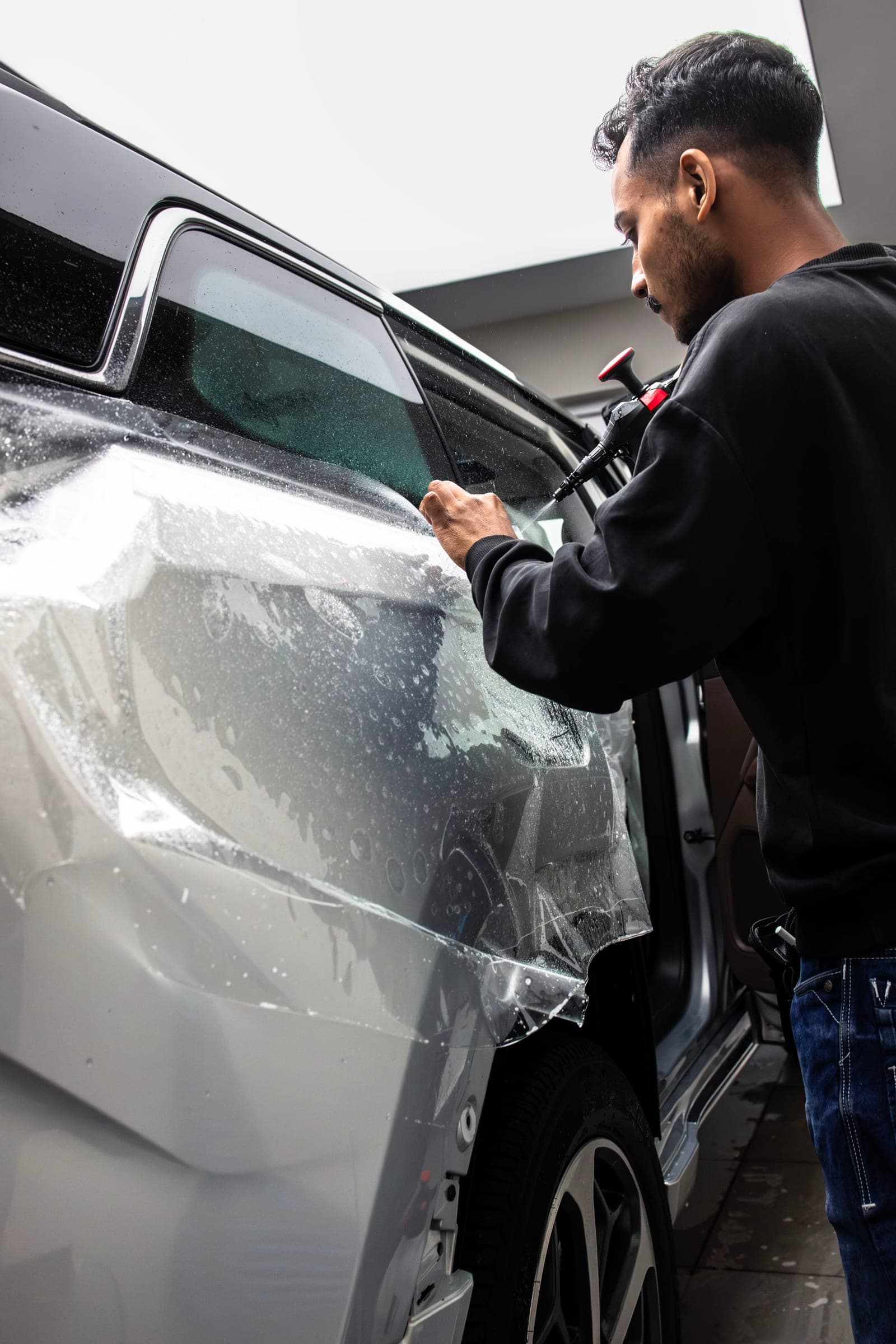 Installer applying paint protection film to the rear door of a white BYD