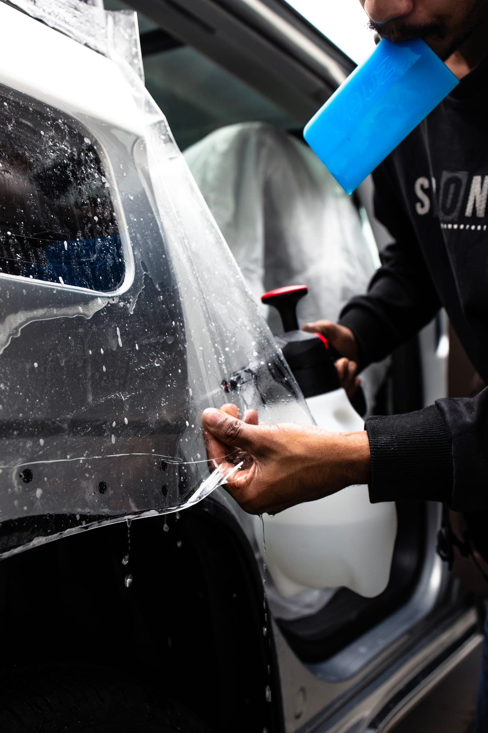 Squeegee pressing paint protection film onto a rear quarter panel