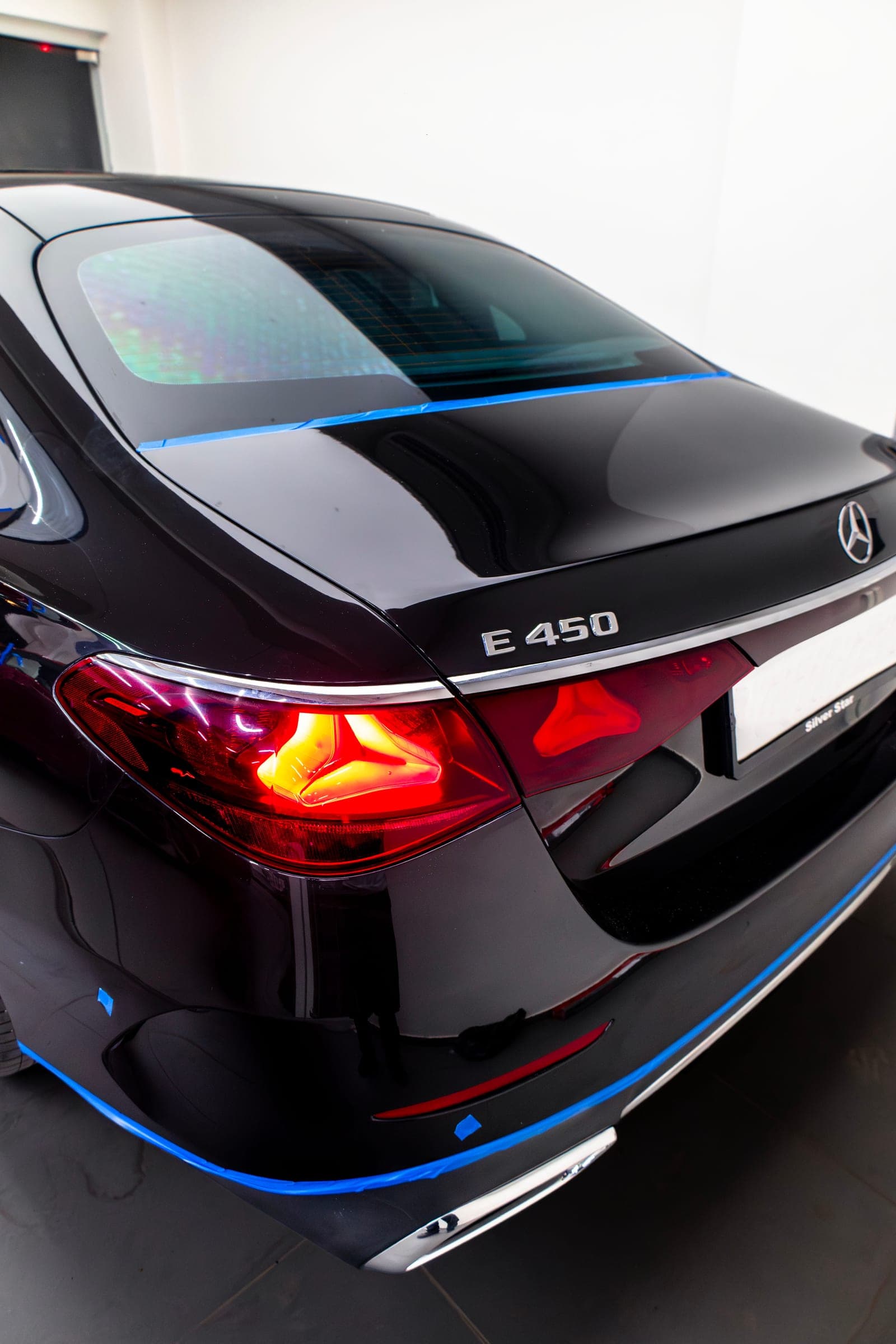 Rear of a black Mercedes-Benz E 450 with its tail-lights lit