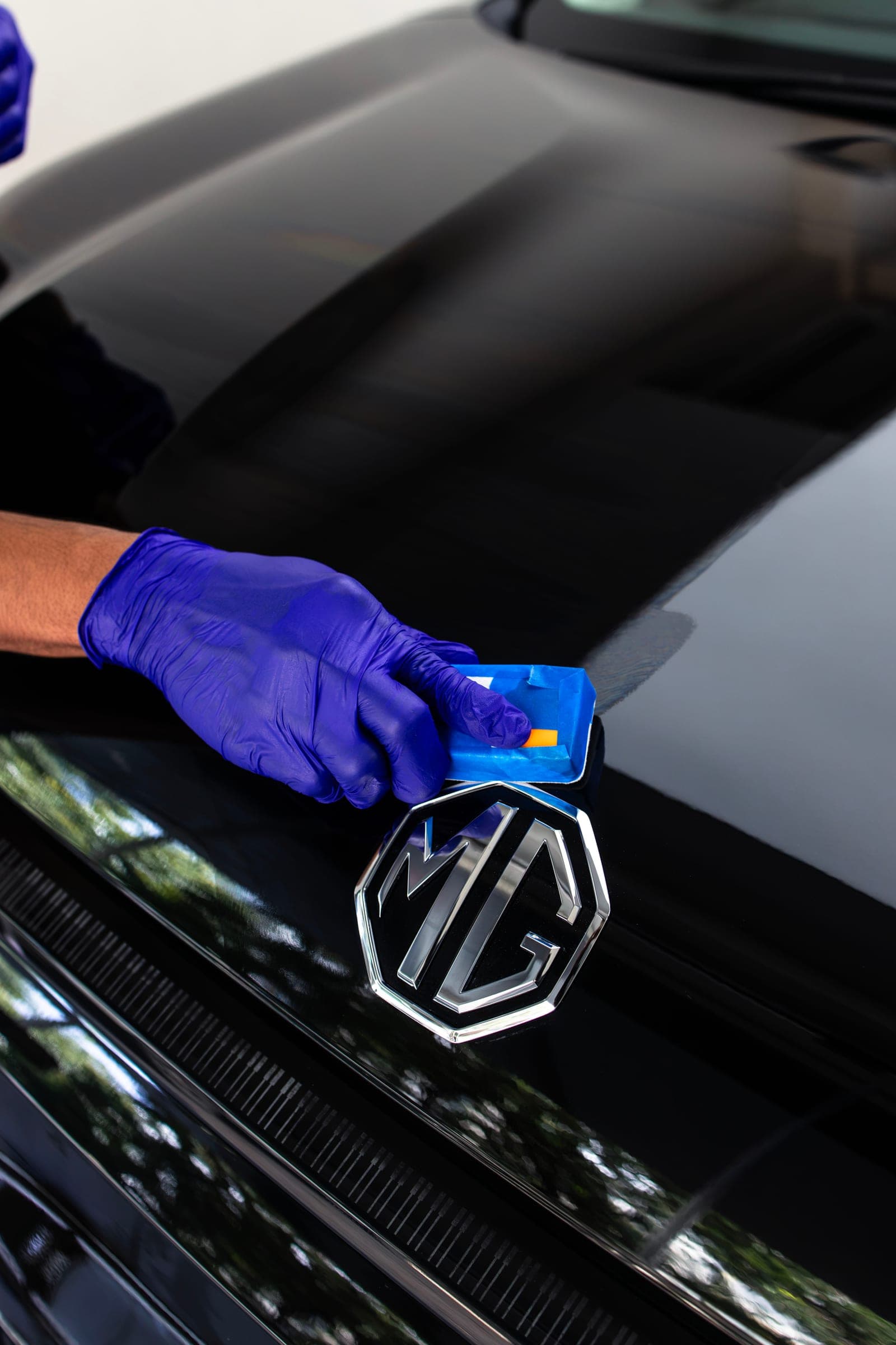 Ceramic coating being applied beside the MG badge with an applicator block