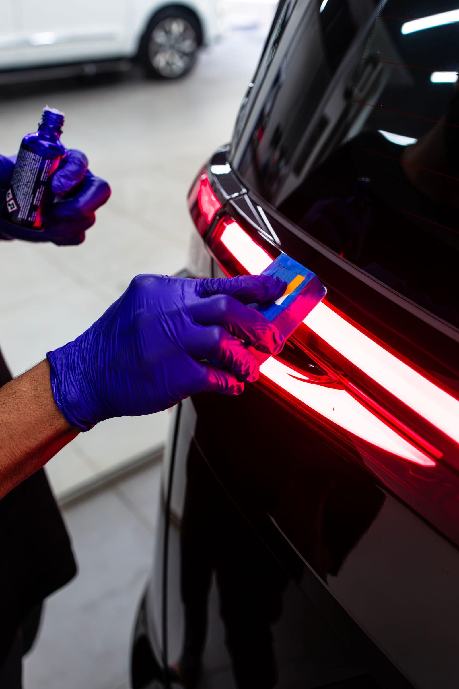 Applicator passing along the illuminated tail-light of an MG M9