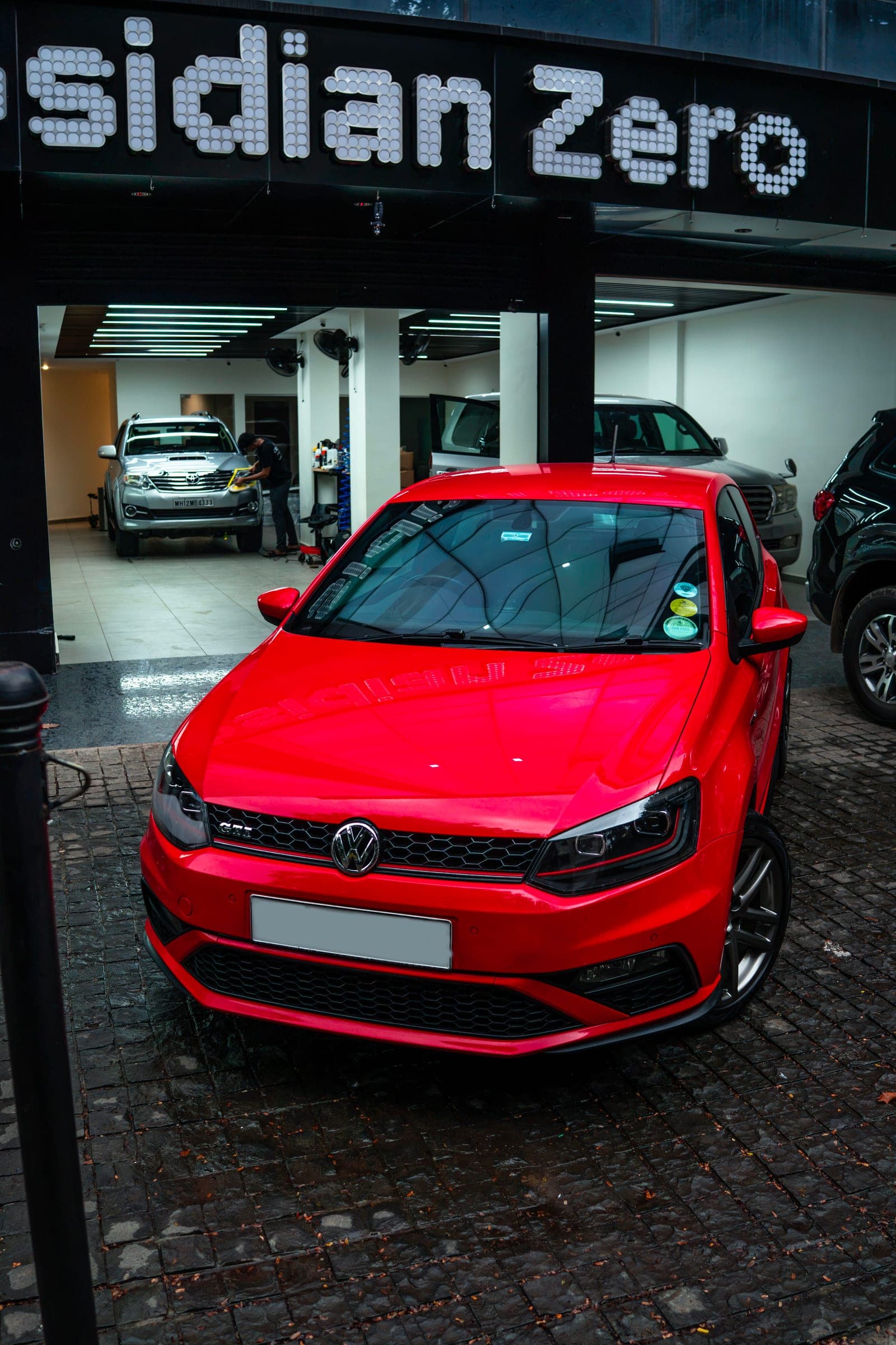 Red Volkswagen Polo GT beneath the illuminated Obsidian Zero sign