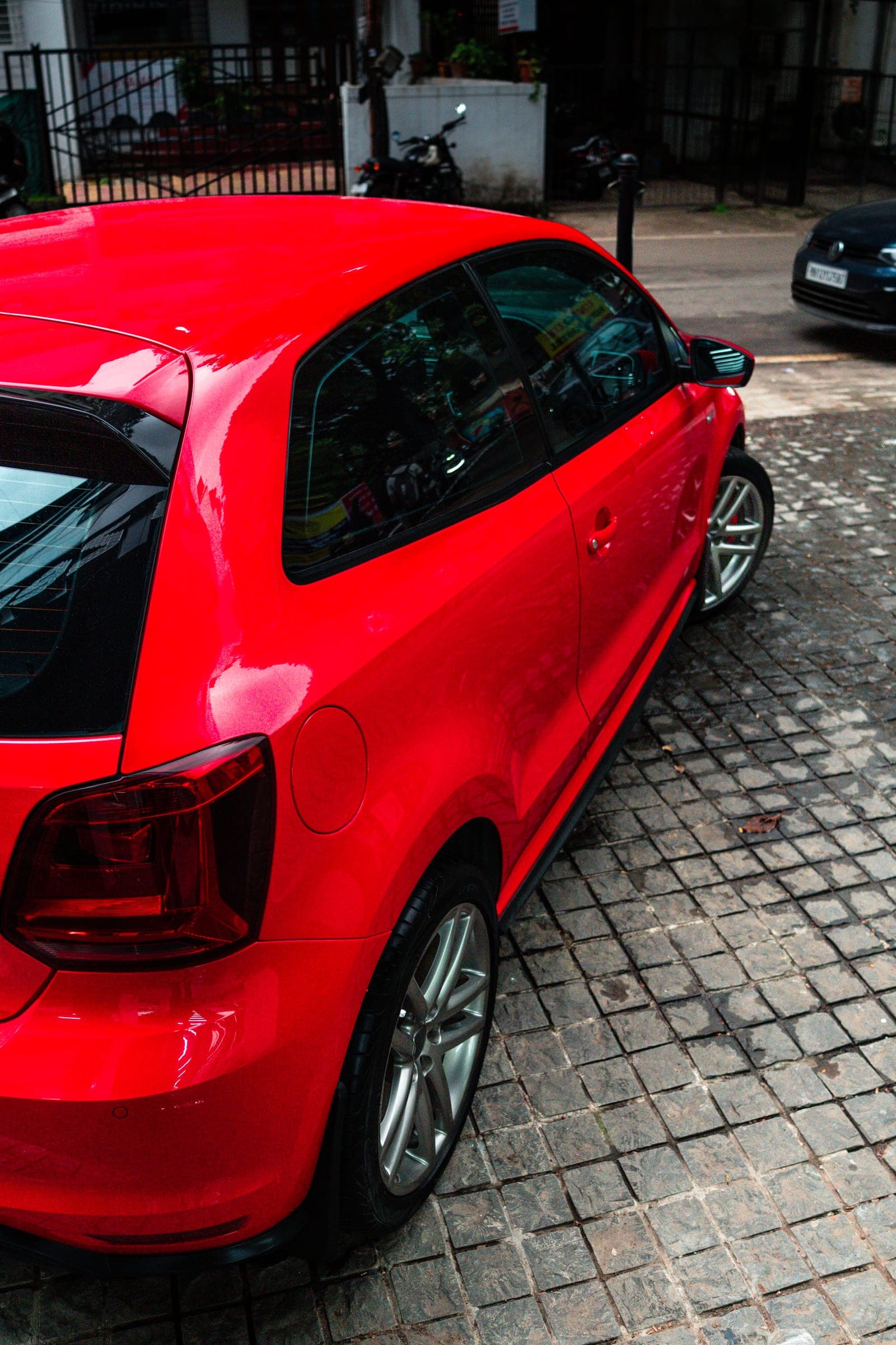 Red Volkswagen Polo GT in profile on wet cobbles