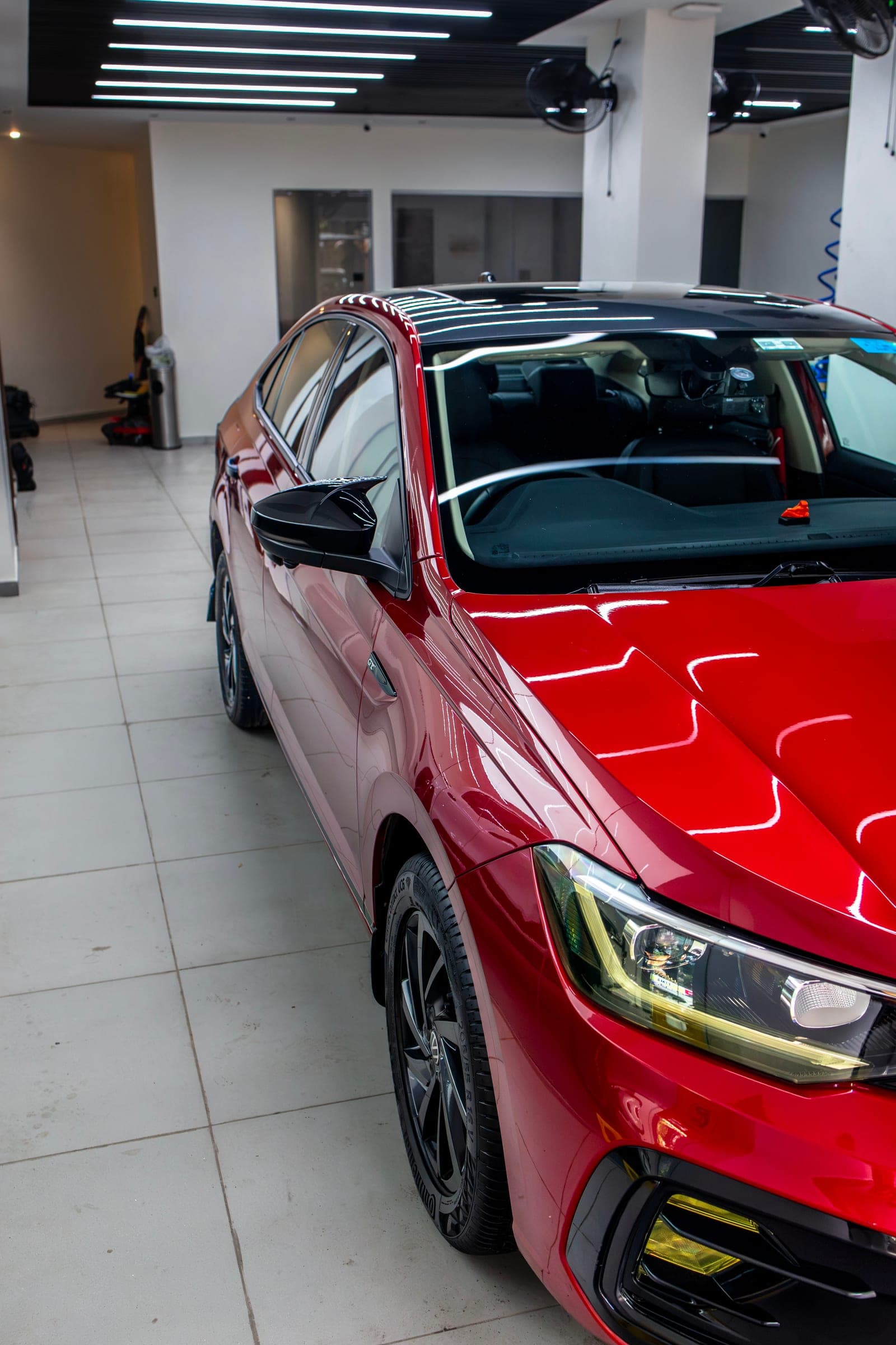 Red Volkswagen Virtus GT, front three-quarter, reflections across the bonnet