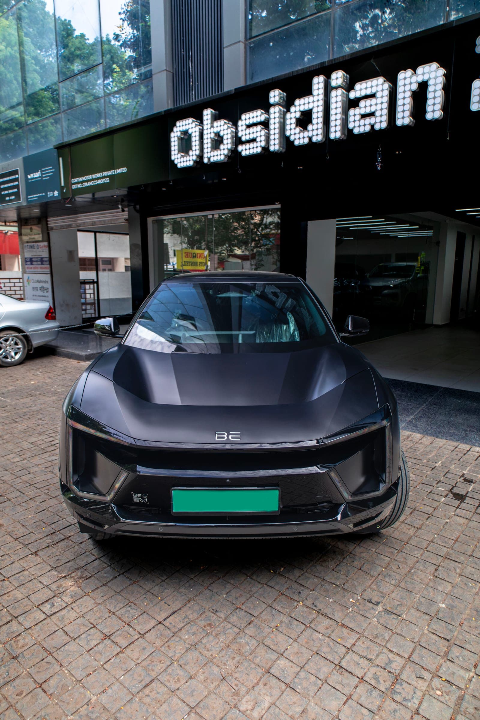 Satin black Mahindra BE 6 parked beneath the illuminated Obsidian Zero sign