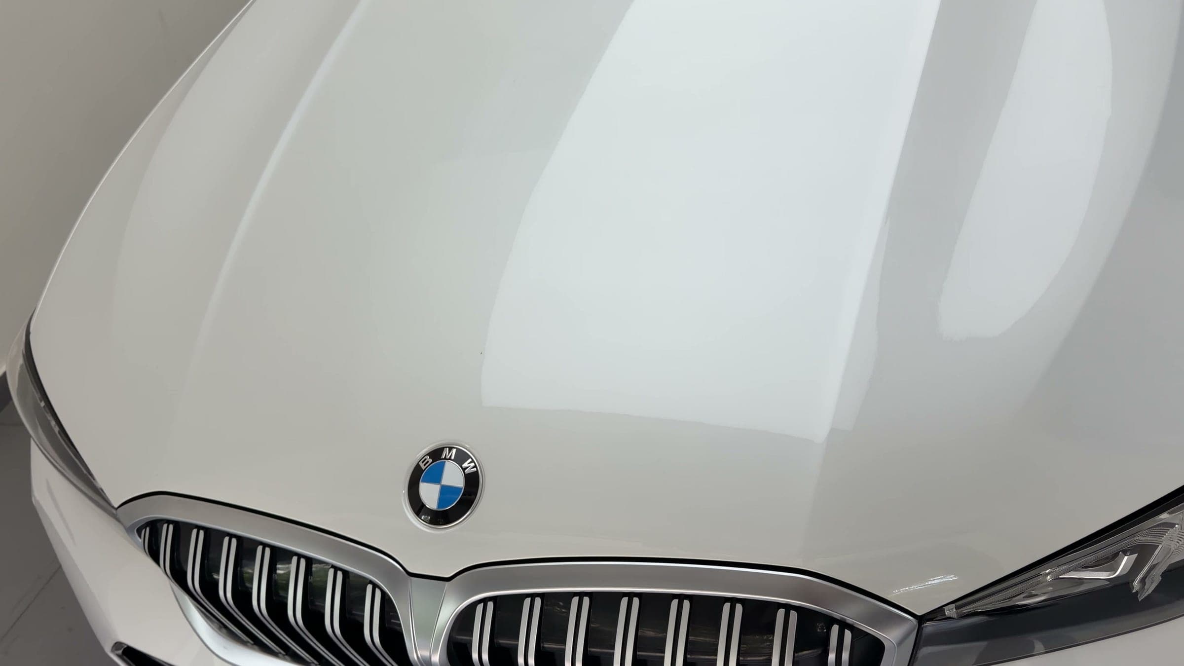 Studio light reflected across the white bonnet and kidney grille of a BMW 330Li