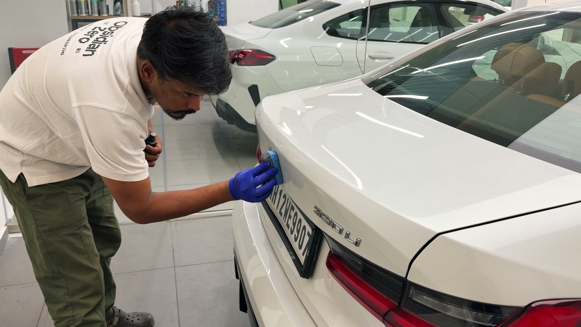 Technician in an Obsidian Zero tee wiping down the boot lid of a BMW 330Li