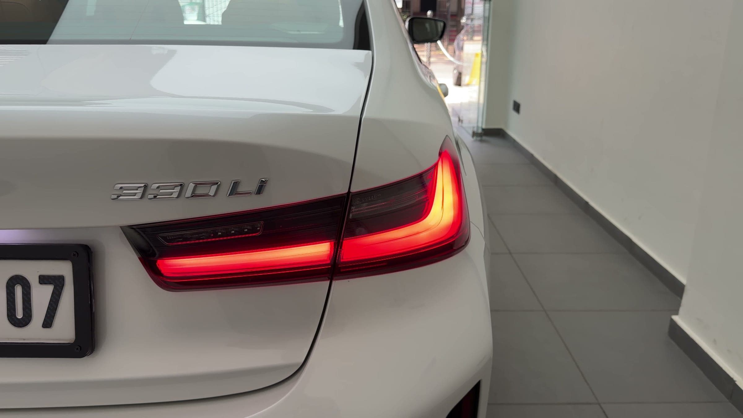 Illuminated tail-light and 330Li badge on a white BMW