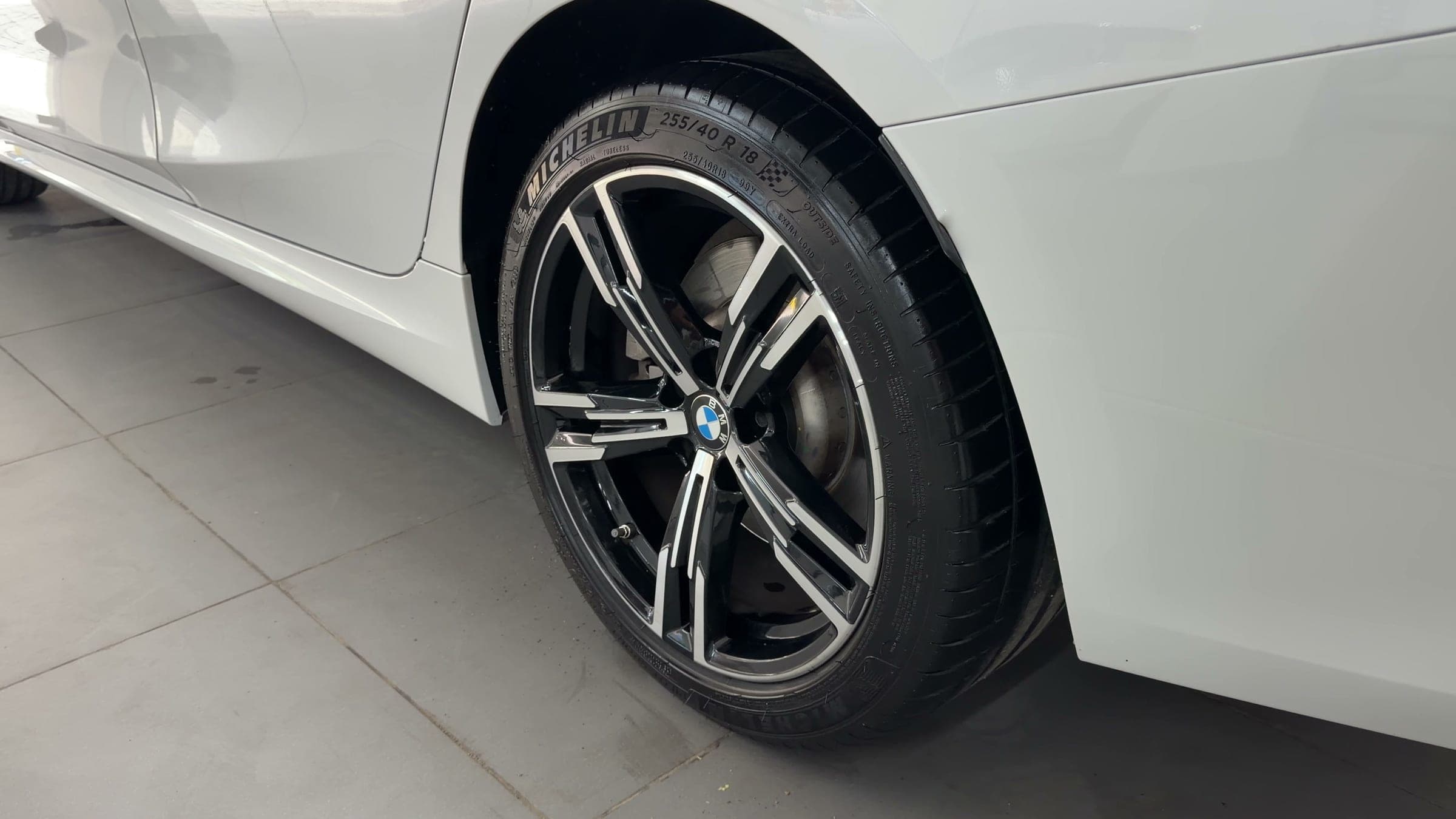 Alloy wheel and front wing of a white BMW 330Li