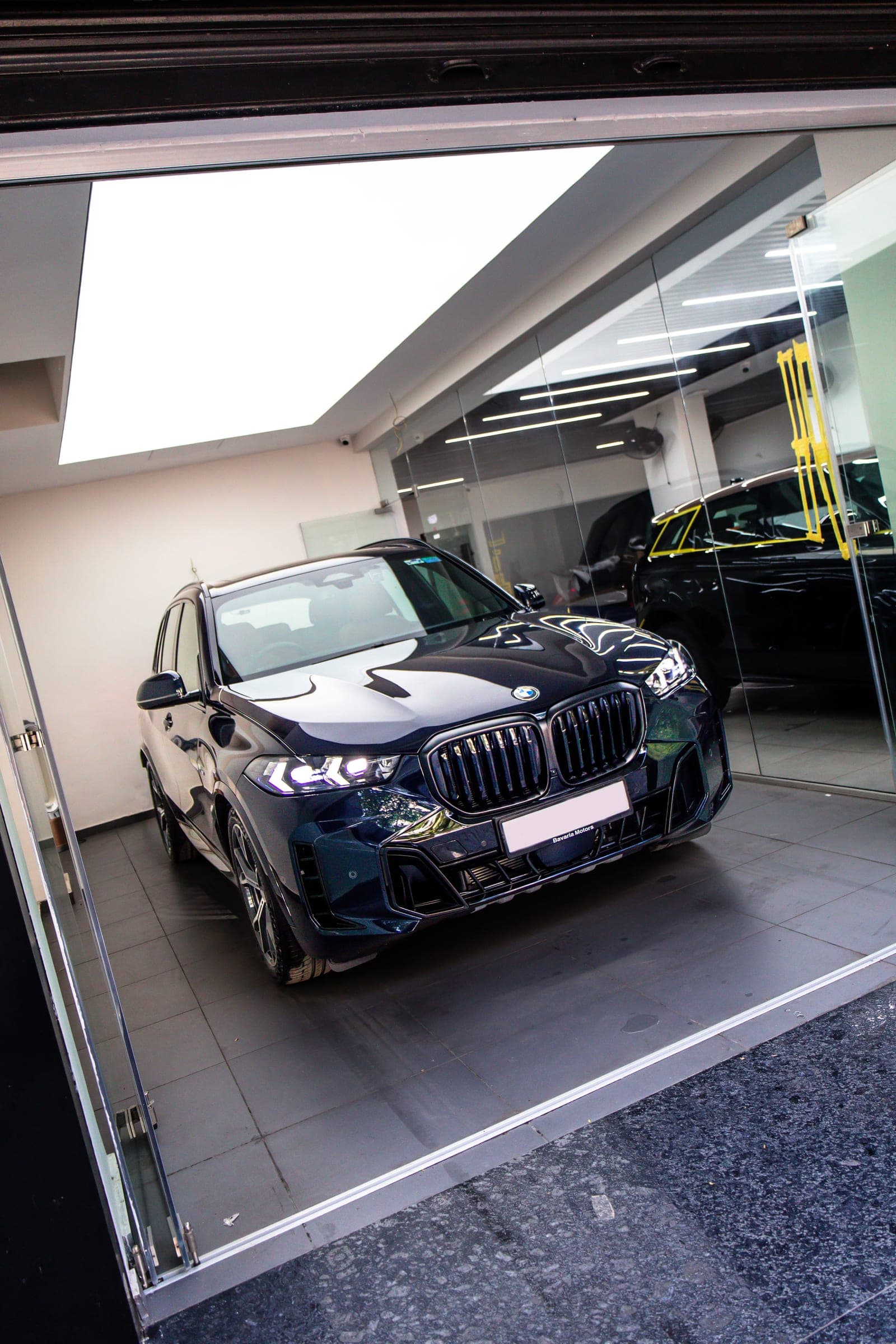 Dark blue BMW X5 in the studio, seen through a glass partition