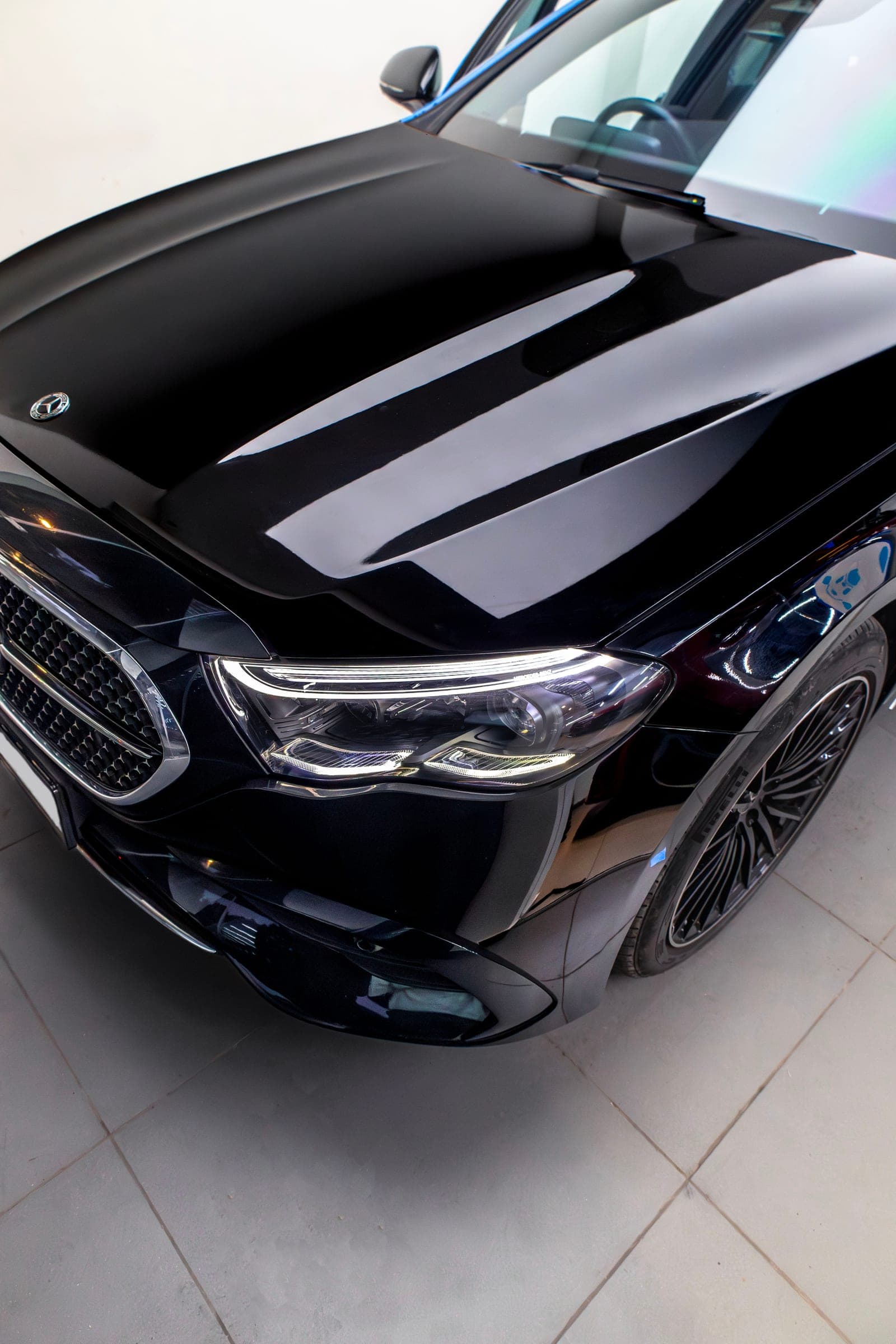 Gloss black bonnet of a Mercedes-Benz E 450 reflecting the studio lights