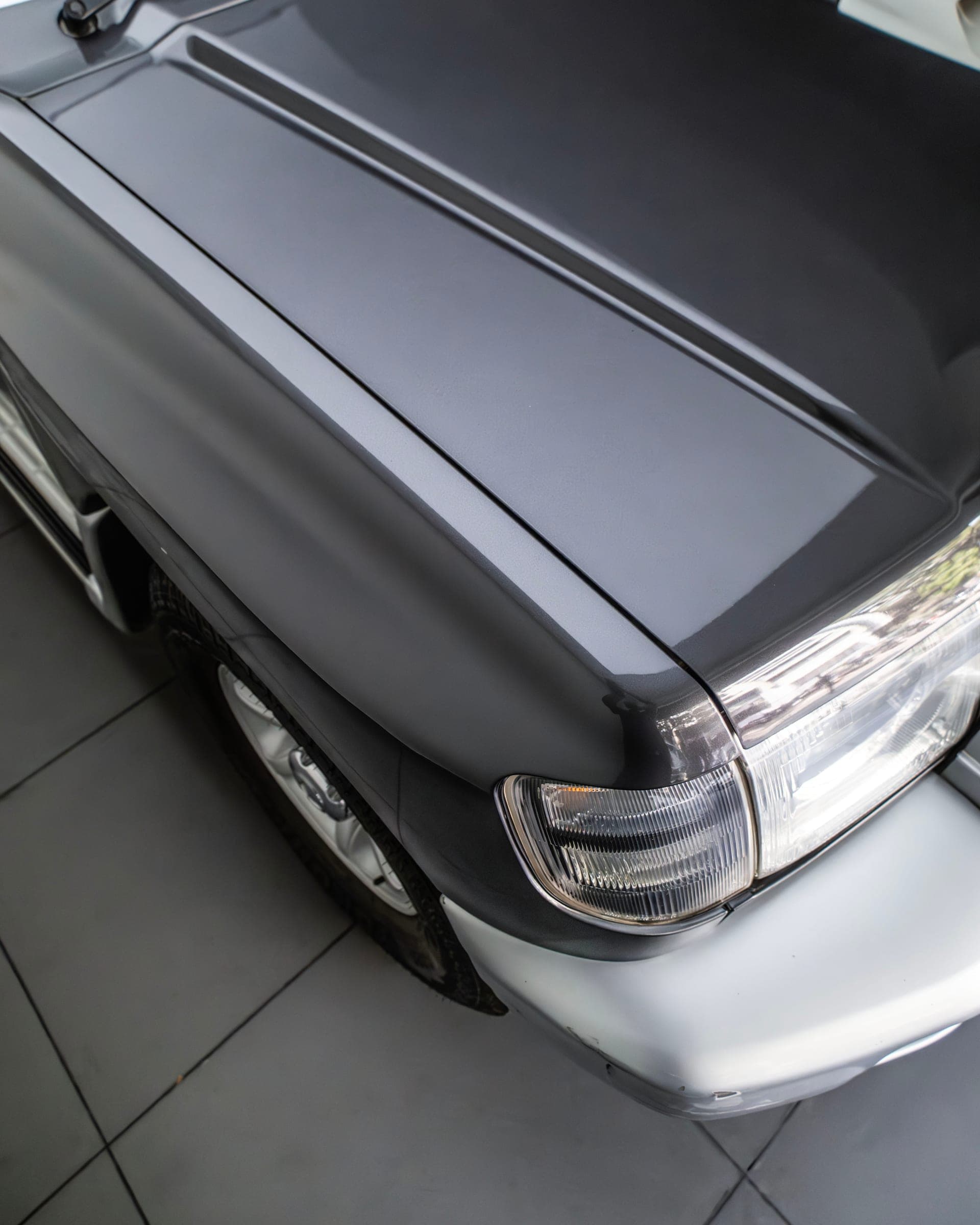 Black bonnet and headlight of a Mitsubishi Pajero