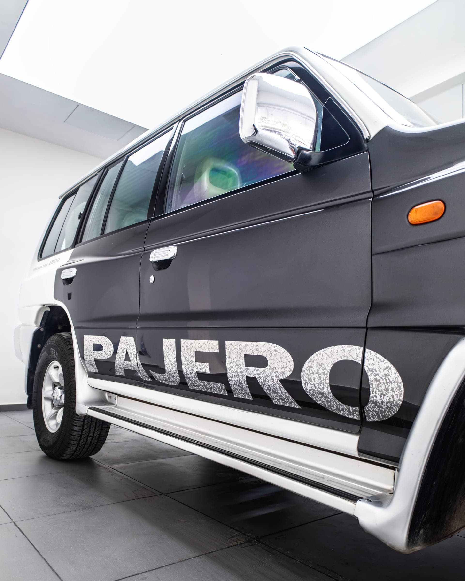 Pajero side graphic across the black lower body of a two-tone Mitsubishi Pajero