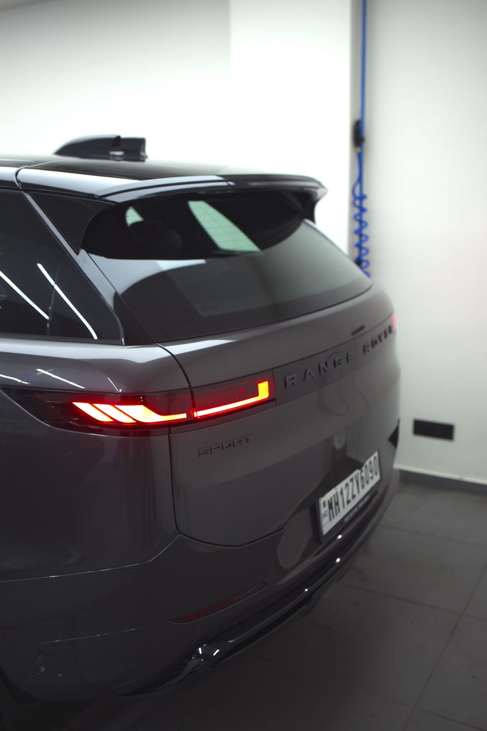 Rear three-quarter of a grey Range Rover Sport with tail-lights lit
