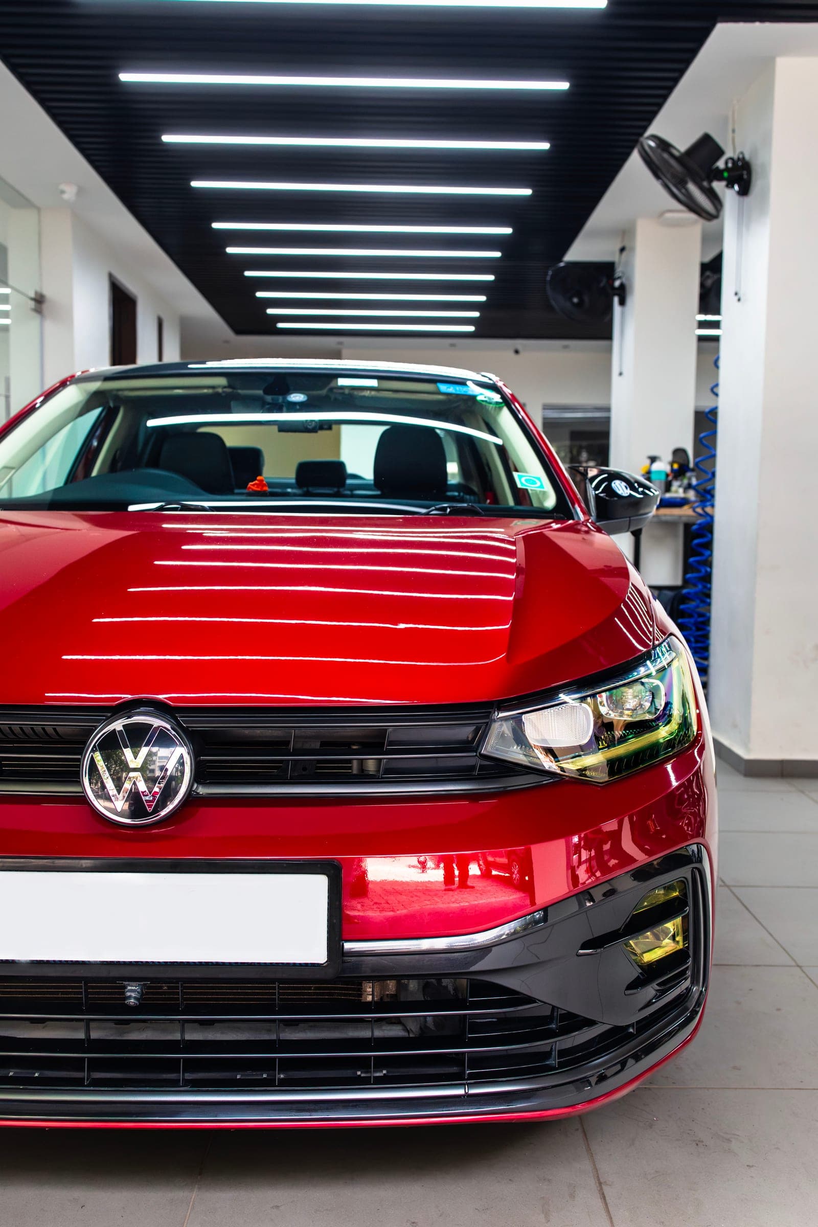 Red Volkswagen Virtus GT in the studio beneath linear ceiling lights