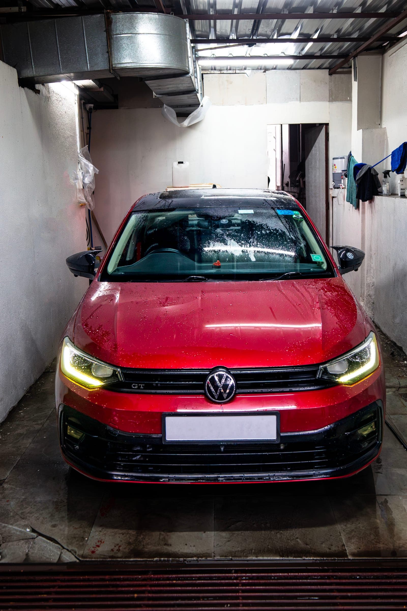Red Volkswagen Virtus GT facing out of the wet wash bay
